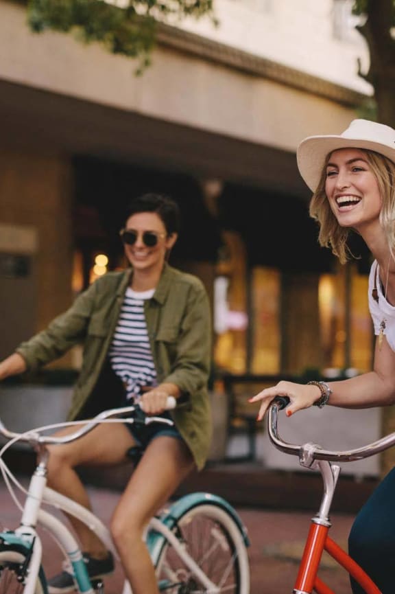 two women riding bikes down the street