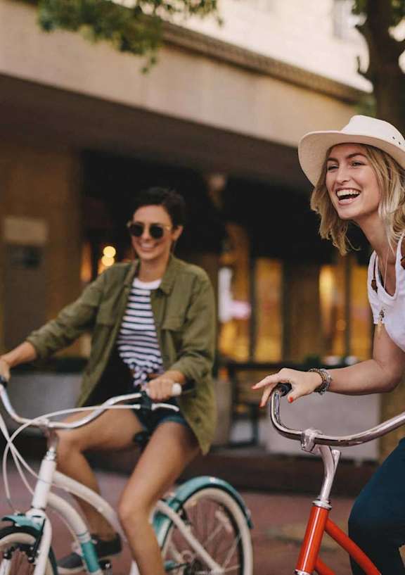 two women riding bikes down the street