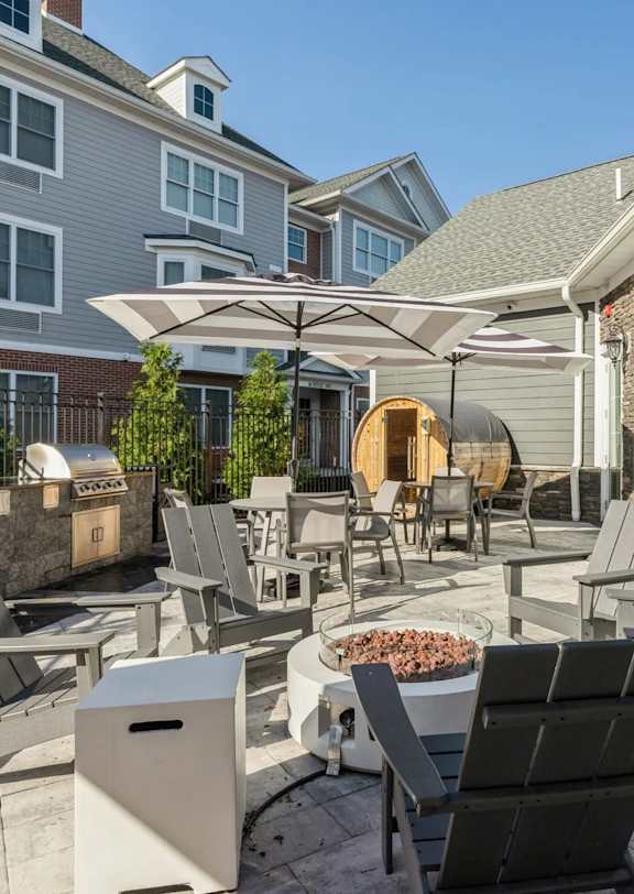 A patio with chairs and a table with a fire pit in the middle.