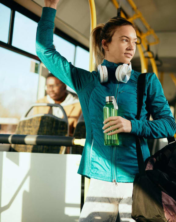 a woman on a bus holding a bottle and a bag