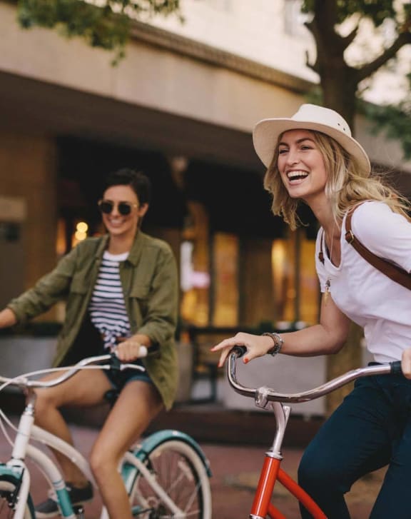 two women riding bikes down the street