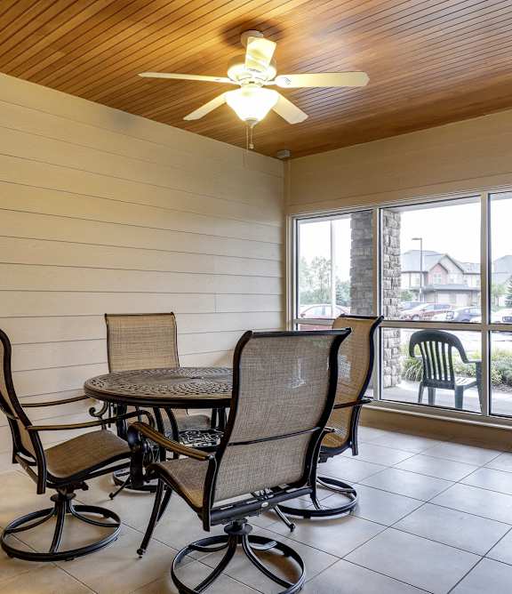 A table with four chairs is in a room with a ceiling fan.