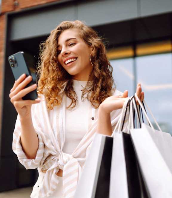 Woman holding shopping bags and looking in phone at St. Andrews Apartment Homes, Georgia