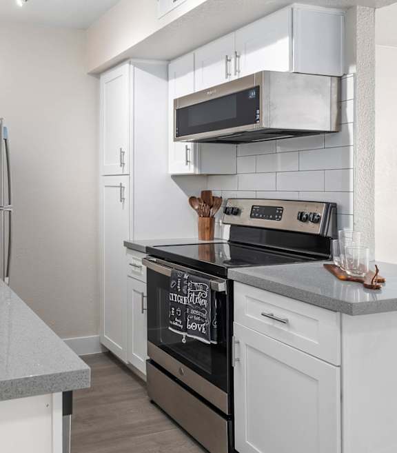 A modern kitchen with a black oven and white cabinets.