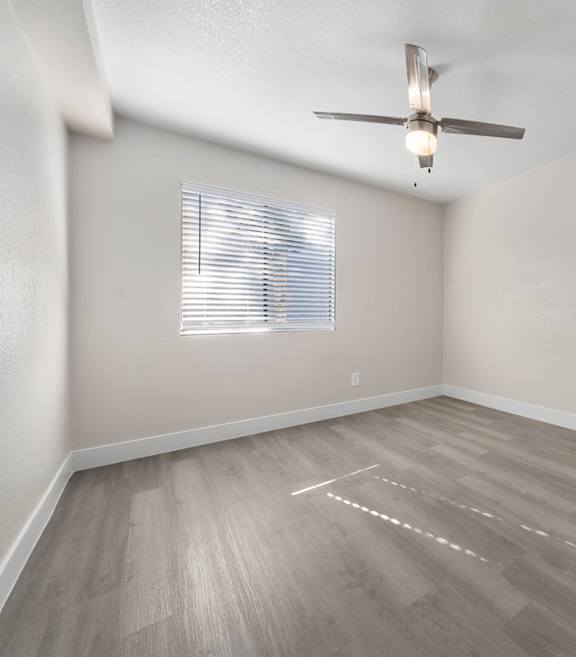 A room with a ceiling fan and a window with blinds.