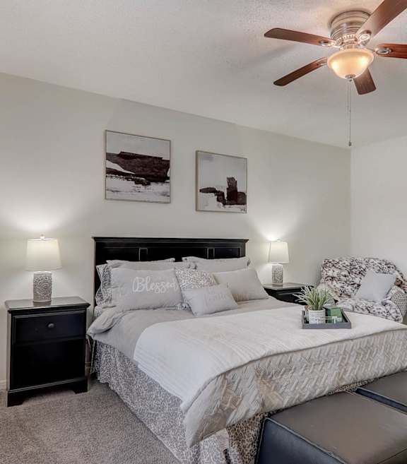 A bedroom with a bed, nightstand, and a ceiling fan.