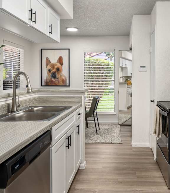 A kitchen with a stainless steel refrigerator and black appliances.