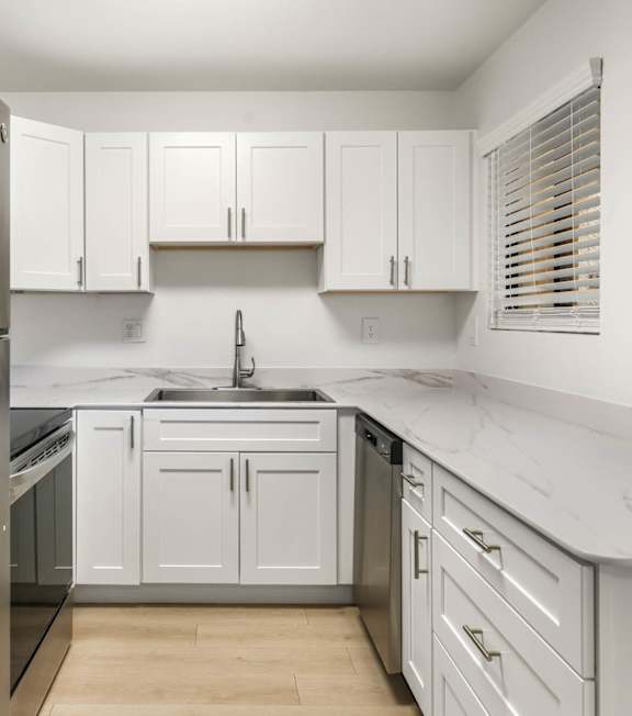 A kitchen with white cabinets and a stainless steel refrigerator.