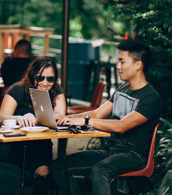 Three people sitting at a table with laptops.