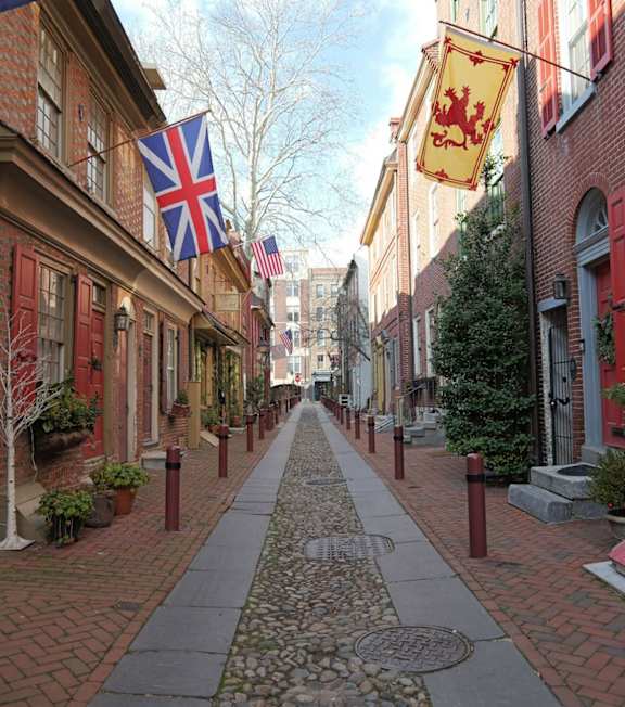 A cobblestone street with a flag on the left and a flag on the right.