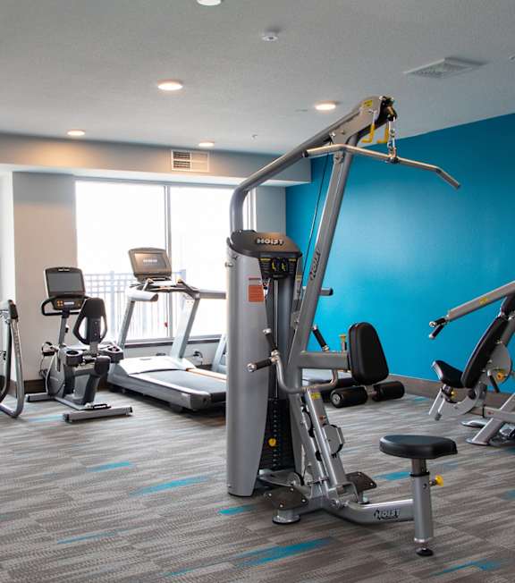A gym with a variety of exercise equipment including treadmills, stationary bikes, and weight machines at Avonlea in Lakeville, MN