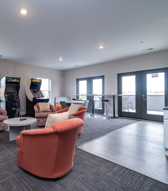 a living room with couches and chairs and a video game on the wall