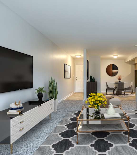A modern living room with a grey couch, a coffee table, and a flat-screen TV on the wall.