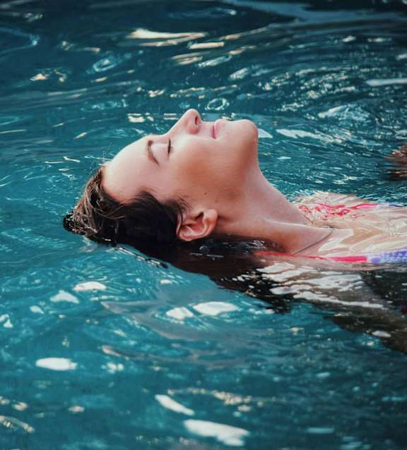 A person is floating in a pool with their eyes closed.at The Garden District Apartments, Germantown, TN