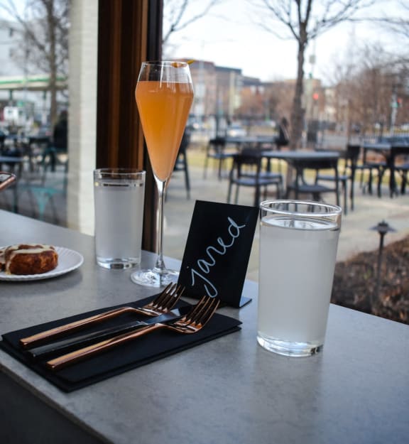 a person sitting at a table with a cell phone and a glass of juice at Coda on H Apartments, Washington, DC