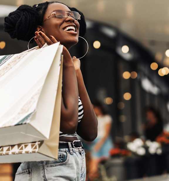 A woman is holding a shopping bag and smiling.