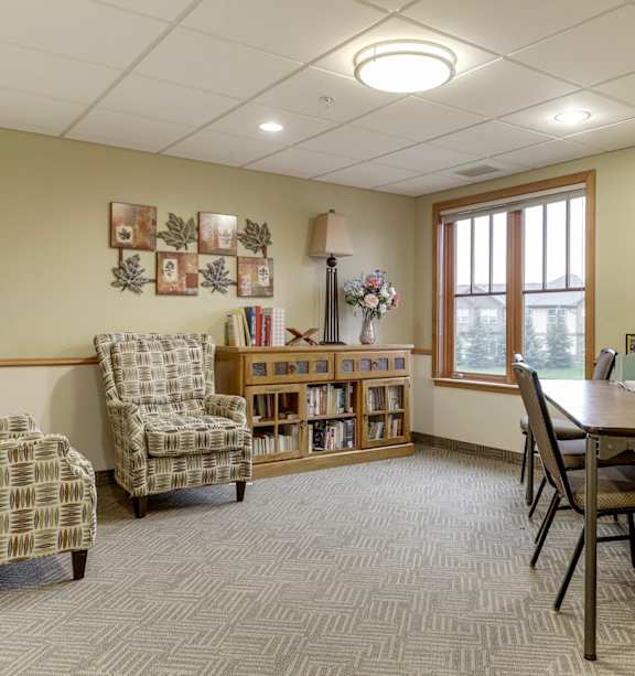 A room with a desk, chairs, and bookshelves.