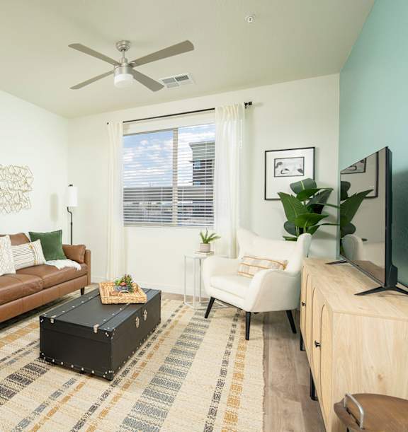 A living room with a red couch, a television, and a potted plant.