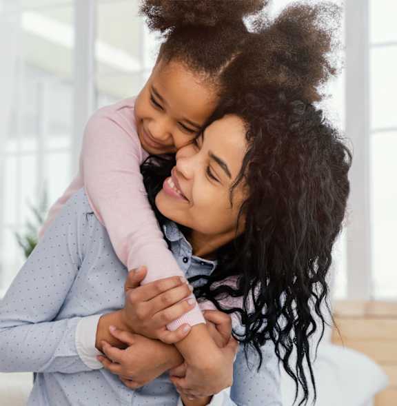 A woman is hugging a child tightly.