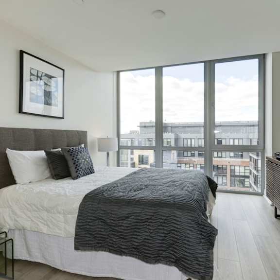 A bedroom with a large bed and a balcony overlooking the city.