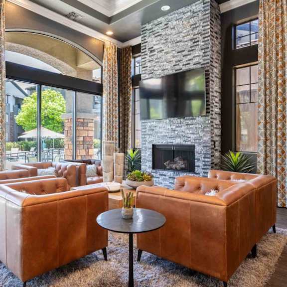 A living room with a stone fireplace and a brown leather couch.