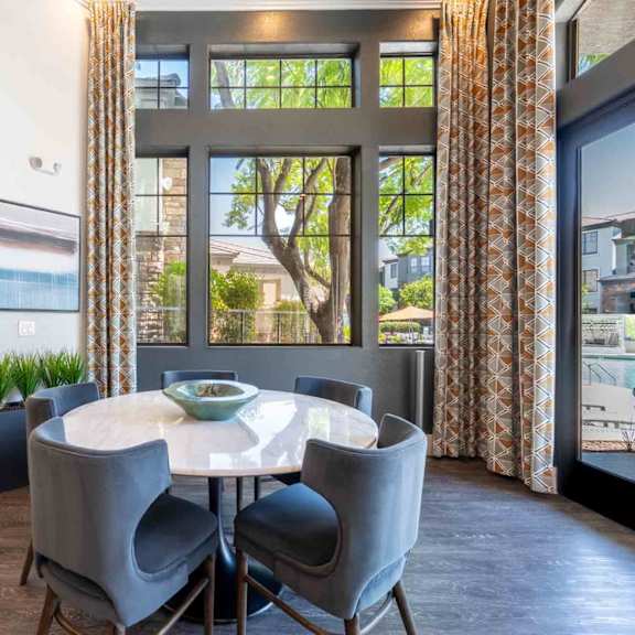 A dining room with a table and chairs and a view of the outside.