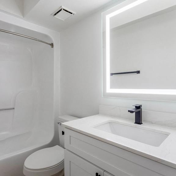 A white bathroom with a toilet, sink, and shower.