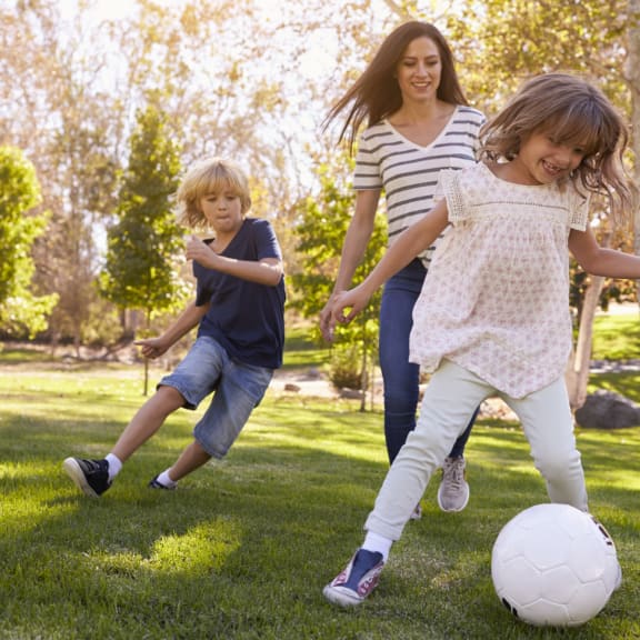 Family playing soccer in the park