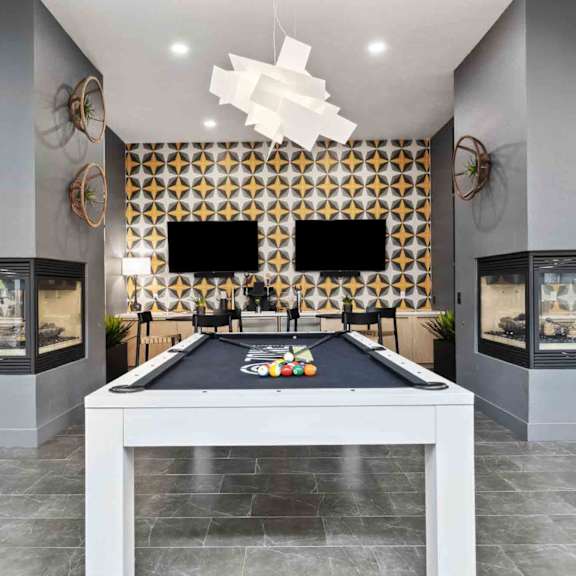 A pool table is in the middle of a room with a black and gold patterned wall.