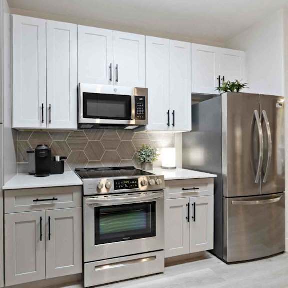 A modern kitchen with a stove top oven, microwave, and refrigerator.