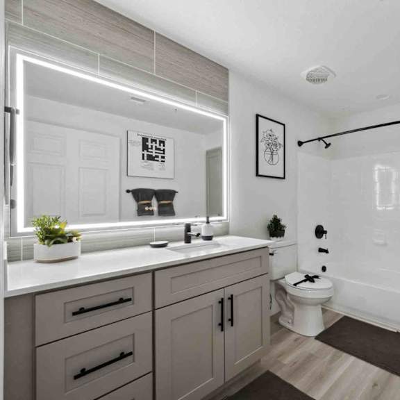 A bathroom with a white countertop and grey cabinets.