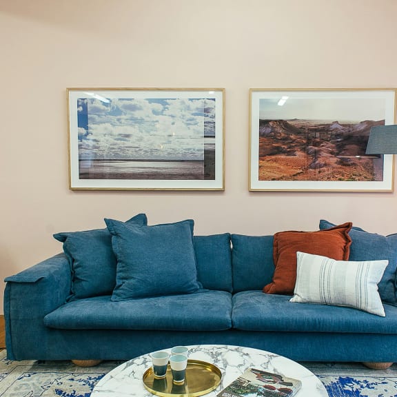 a living room with a blue couch and two pictures on the wall