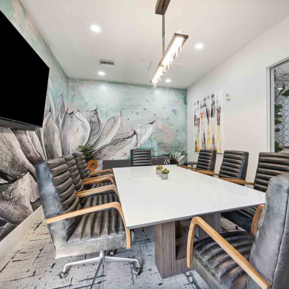 a meeting room with a white table and chairs and a large mural on the wall