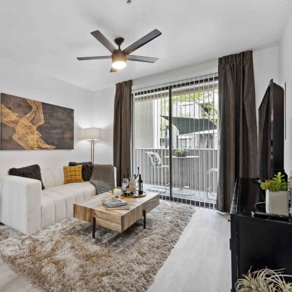 a living room with a white couch and a wooden coffee table on a furry rug