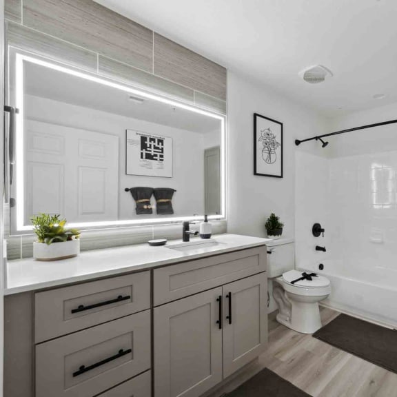 an all white bathroom with gray cabinets and a black shower curtain