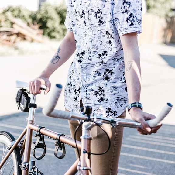 A person in a floral shirt is holding a bicycle.