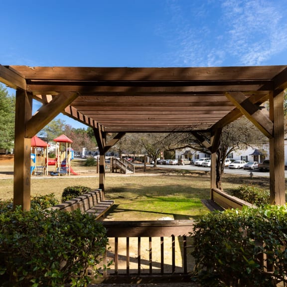 a wooden pavilion in a park with a playground