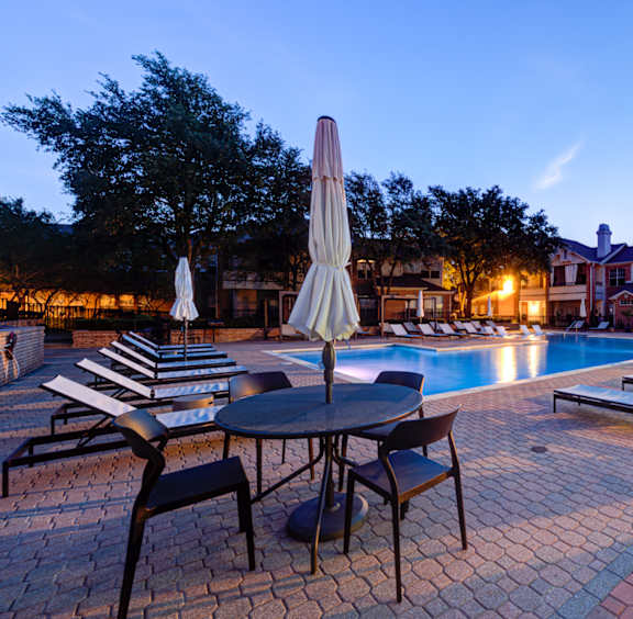 a swimming pool with tables and chairs at night