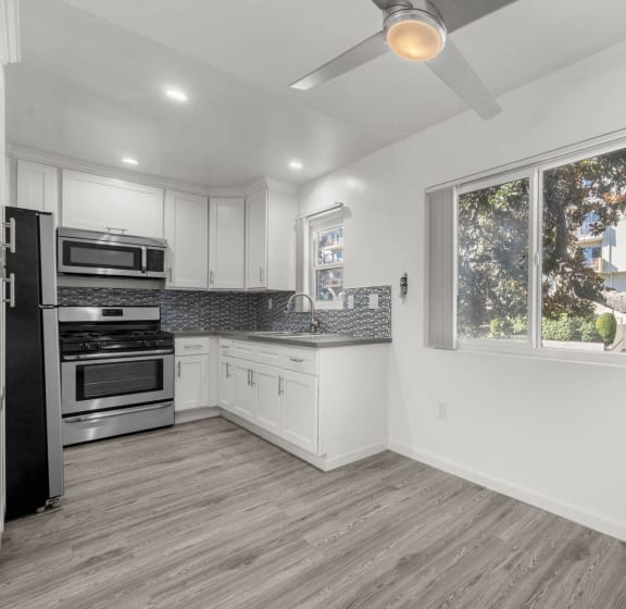 a kitchen with white cabinets and a window