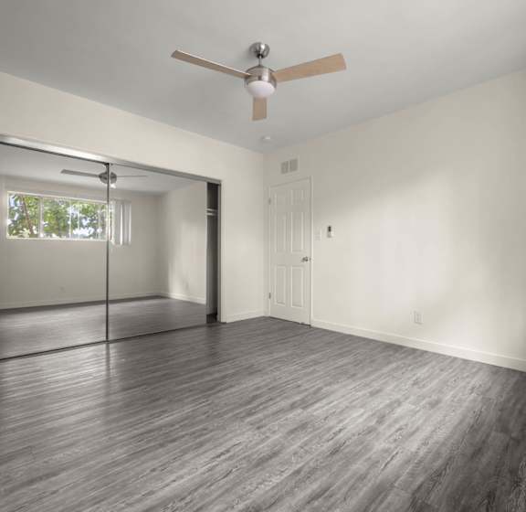an empty living room with a ceiling fan and a window