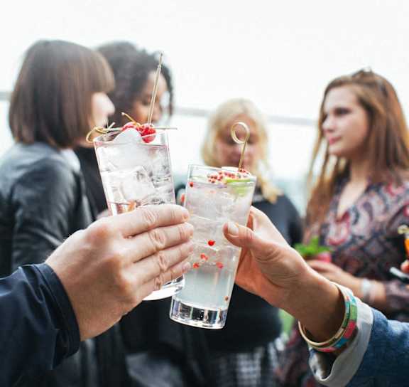 people holding up glasses of water at a party