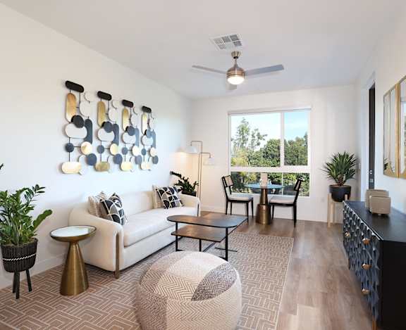 Park on First Apartments Model Living Room with couch, table with chairs, and window