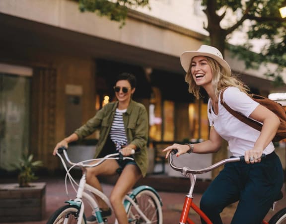 two women riding bikes down the street
