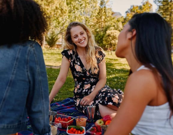 three women sitting at a picnic in the park