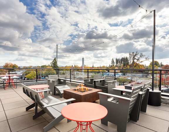 A patio with tables and chairs overlooking a parking lot.