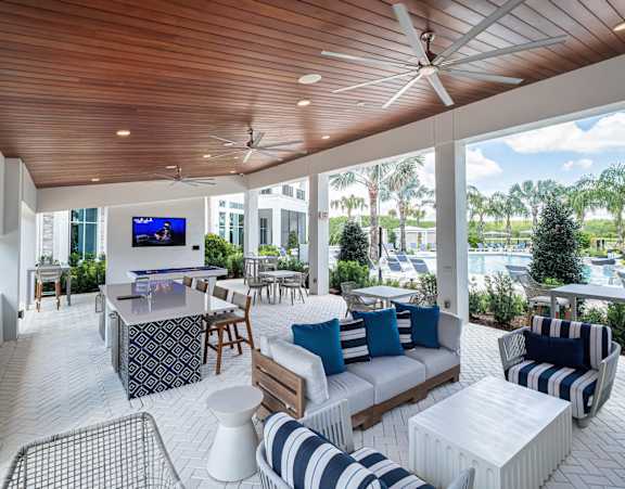 A modern outdoor living space with a wooden ceiling and a television mounted on the wall. at Altis Twin Lakes Apartments, Kissimmee, FL 34744