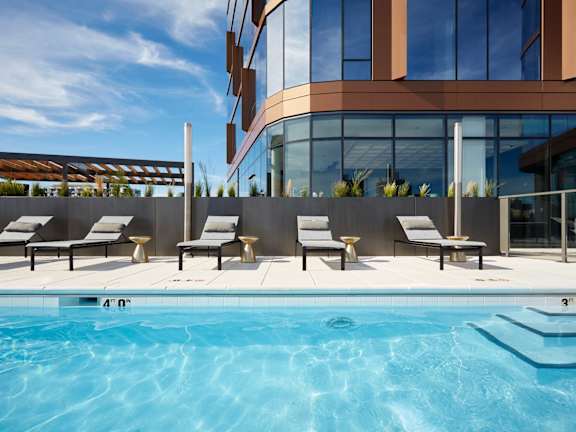 A swimming pool with lounge chairs and a modern building in the background.