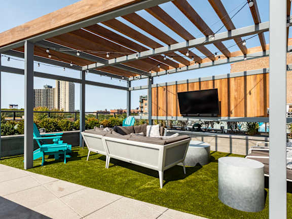 A patio with a white couch and a TV on the wall.