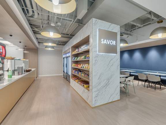 A modern office break room with a marble pillar and a sign that says "Savor".