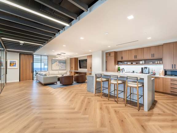 A modern kitchen with wooden floors and a bar area.